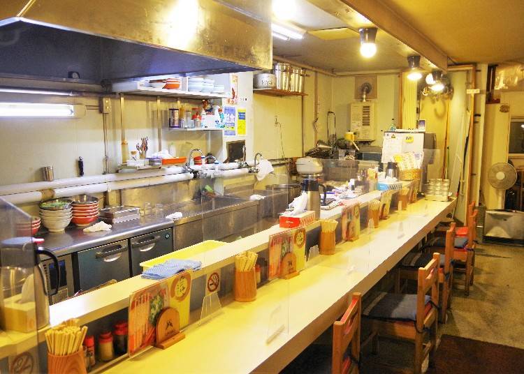 The restaurant has counter seating facing the kitchen and two four-seated tables in the back.