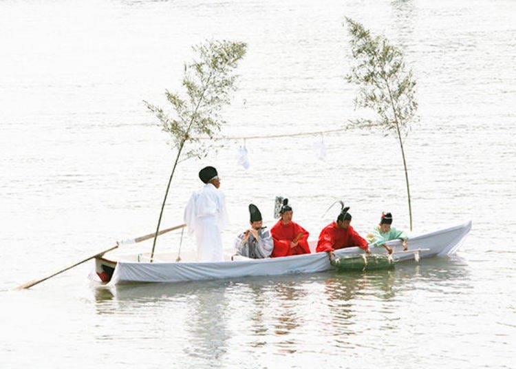 ▲The so-called “wonder child” in the sacred boat (known as ikitsubune) throws the halberd into the water to pray for peace and safety and to protect the city from evil (© Osaka Convention & Tourism Bureau)