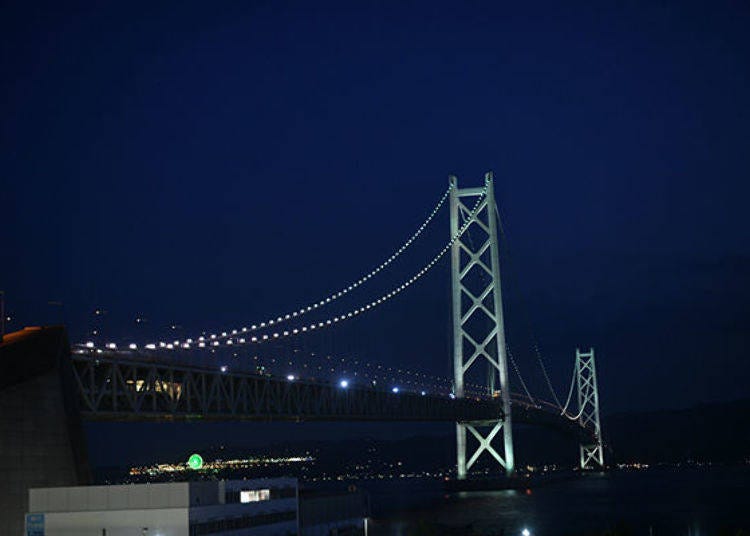 ▲Illuminated Akashi-Kaikyo Bridge. The small, round light visible at the lower left is the Ferris Wheel in the Awaji Service Area on the opposite shore.