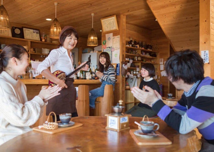 ▲ Madame entertains customers with stories and the sanshin, a three-stringed, snakeskin Okinawan instrument. The warm hospitality created by Madame’s cheerful disposition brings back many repeat customers.