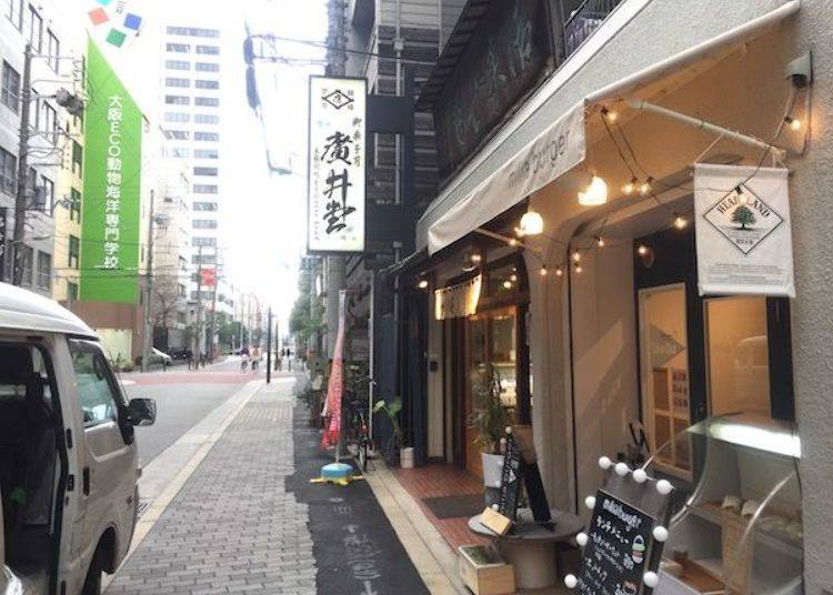 ▲The Japanese-style confectionery shop in the back, famous for its chestnut steamed yokan [sweet bean jelly], was founded in 1877. This is one shop that still has memories of the geisha quarter. The awning of the hamburger shop in front stands in stark contrast.