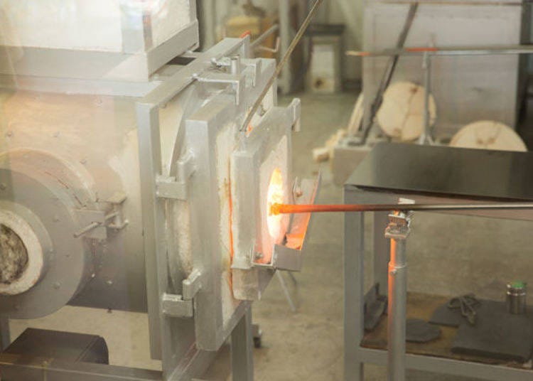 ▲Molten glass from a 1,300-degree furnace is wrapped around the end of a tube