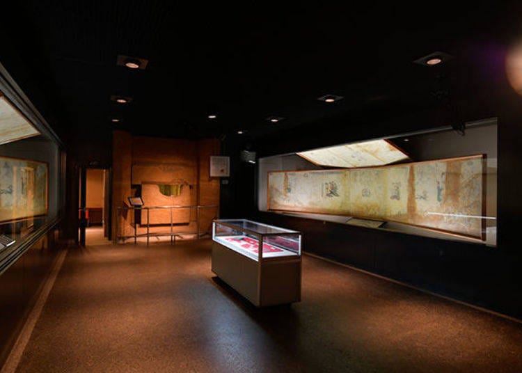 ▲館內展示著忠實重現當時發掘現場畫像的「現狀摹寫」作品（照片右方）及清晰可見的部分復原「復原摹寫」（照片左方）作品。