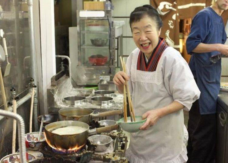 The shopkeeper’s wife finishes up the soup with a charming smile on her face.