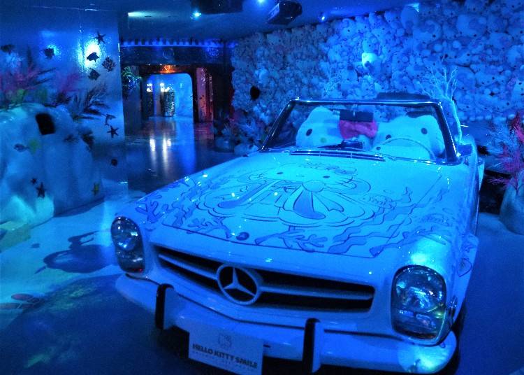 ▲海の洞窟（「CAVE」）を入ると、愛車に乗るハローキティが！車には乗れないけど、青い光の中をドライブするハローキティは、あなたのベストフォトになるはず © 2022 SANRIO CO., LTD. APPROVAL NO. L621898