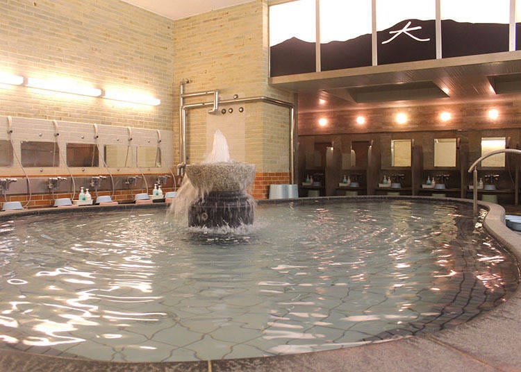 The men's bathing area is spacious and has a large bath. Above the bath, you can see the kanji character from the Daimonji Festival depicted on the glass.