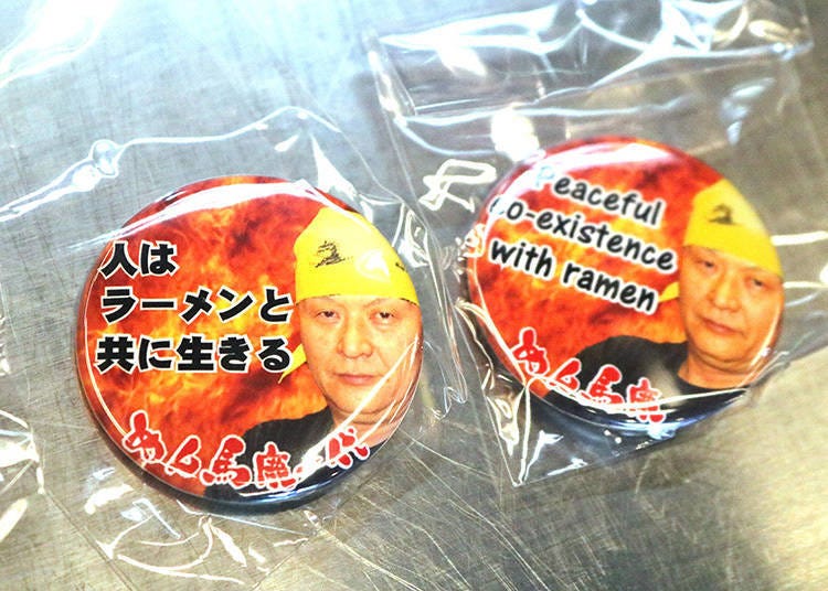 別針徽章印製了店長的照片及與拉麵相關的名言。日文（左）及英文版（右）是一樣的內容。