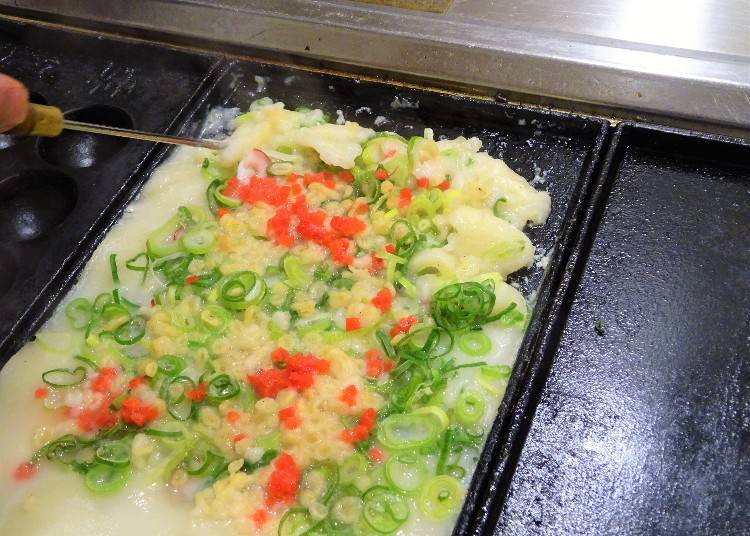 大阪章魚燒DIY步驟2：當麵糊略呈固態後，將麵糊向凹槽集中並翻面！