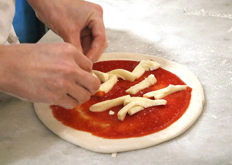 手作りのピザ生地をのばしてトッピング