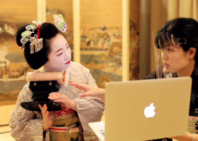 A Maiko (apprentice geisha) explaining the use of their special high pillow for sleeping.