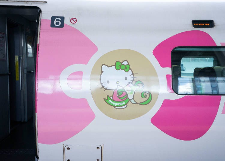 A photo of Okayama Prefecture Hello Kitty holding some Japanese Muscat grapes.