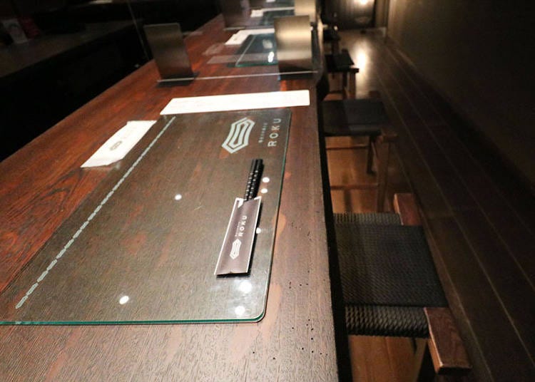 테이블에는 플레이트와 물티슈, 젓가락, 메뉴판이 세팅되어 있다.