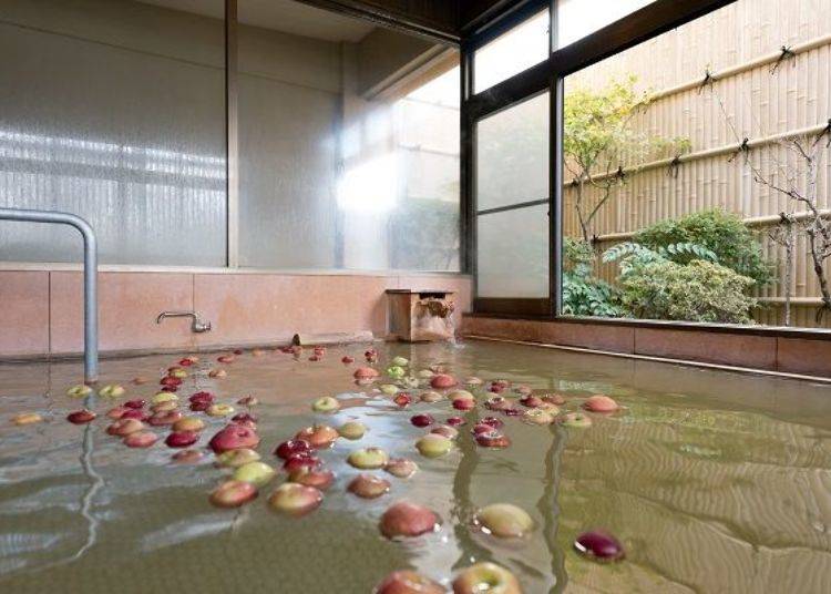 ▲浴池中有许多苹果漂浮着。当日来回泡汤时只限女性入浴。