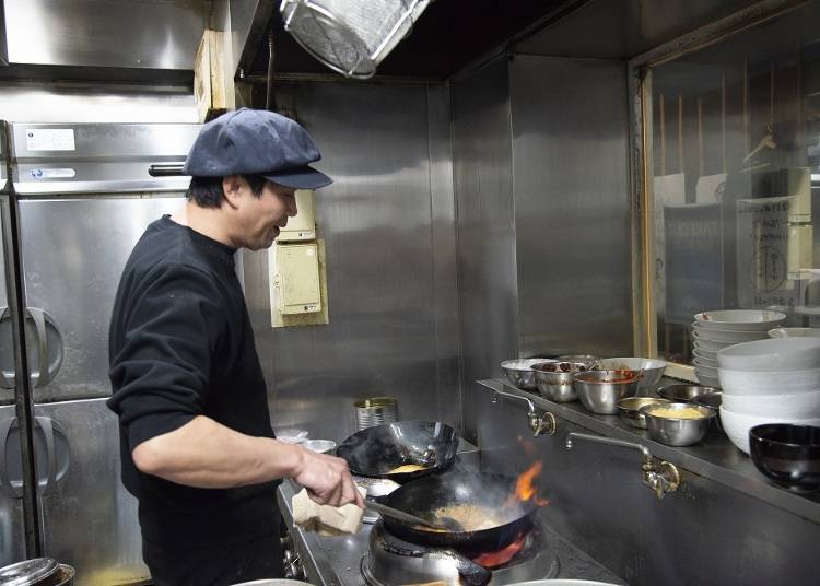 Handling two woks at once, the dish is quickly cooked.