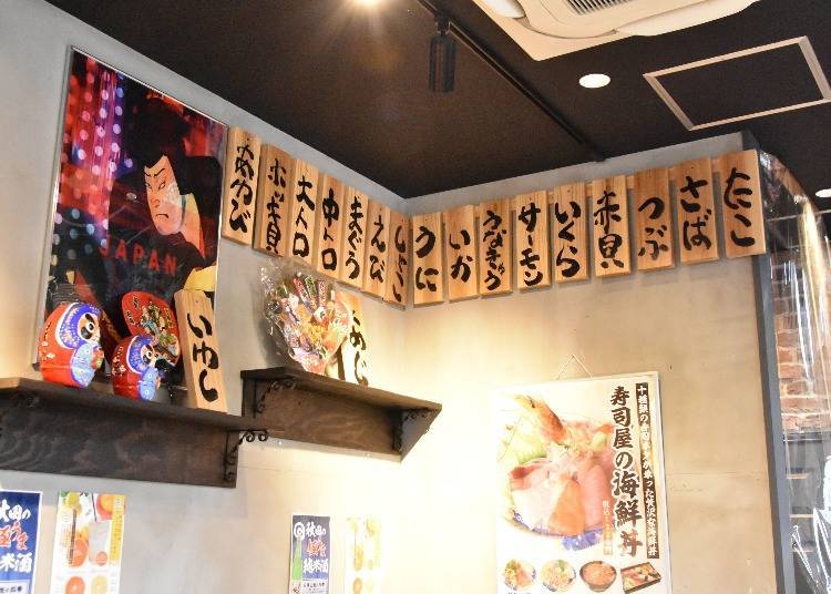 On the shop’s walls, there are wooden tags with the names of sushi toppings listed.