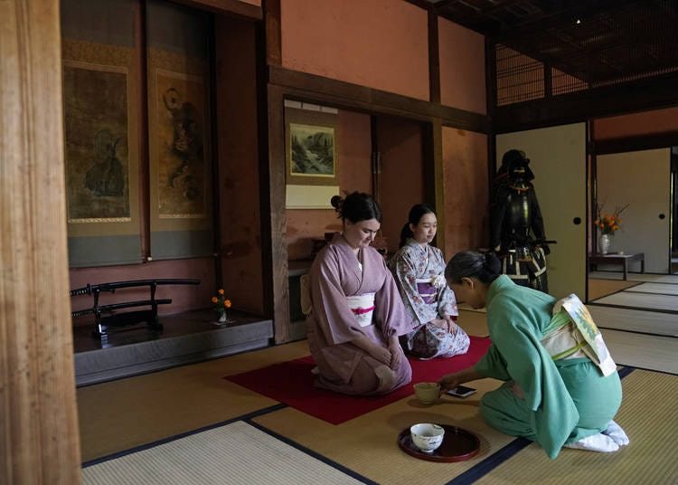 A tea ceremony in a room of samurai swords and a full suit of armor
