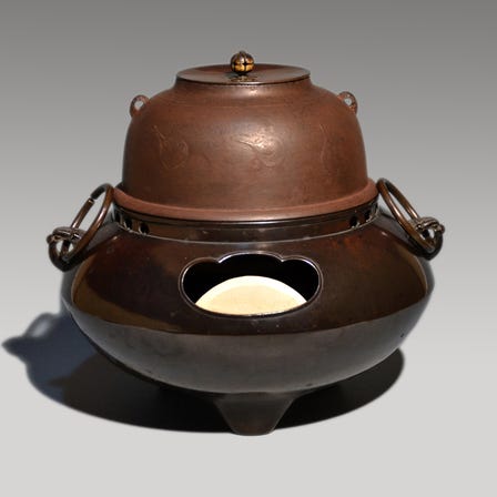 An Ashiya ware shinnari type teakettle with an eggplant design (cast in Hakata) on a daruma-shaped bronze brazier (cast in Chikuzen, it includes a box with a certificate by Isao Nagano.)