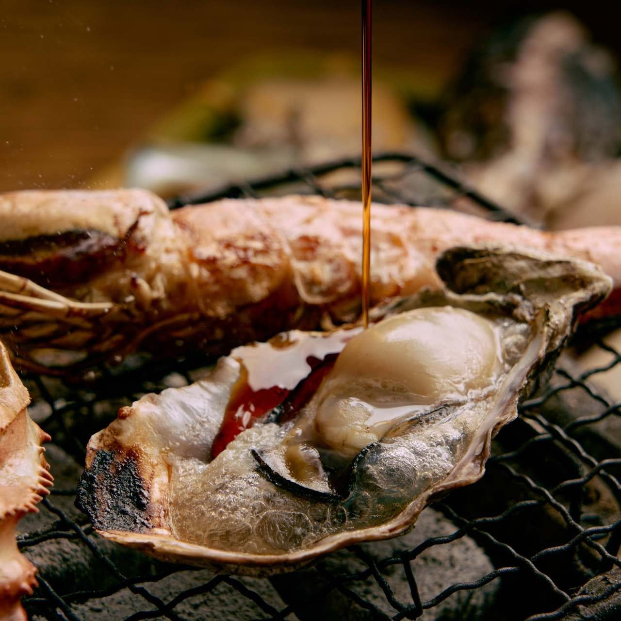 焼き牡蠣にしょうゆをかけている様子
