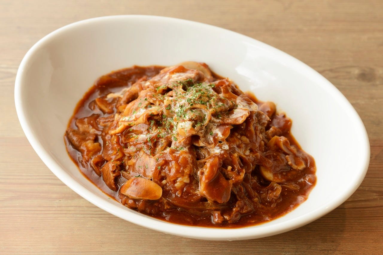 木製のテーブルにハヤシライスが盛り付けられた楕円形の白いお皿が置いてある