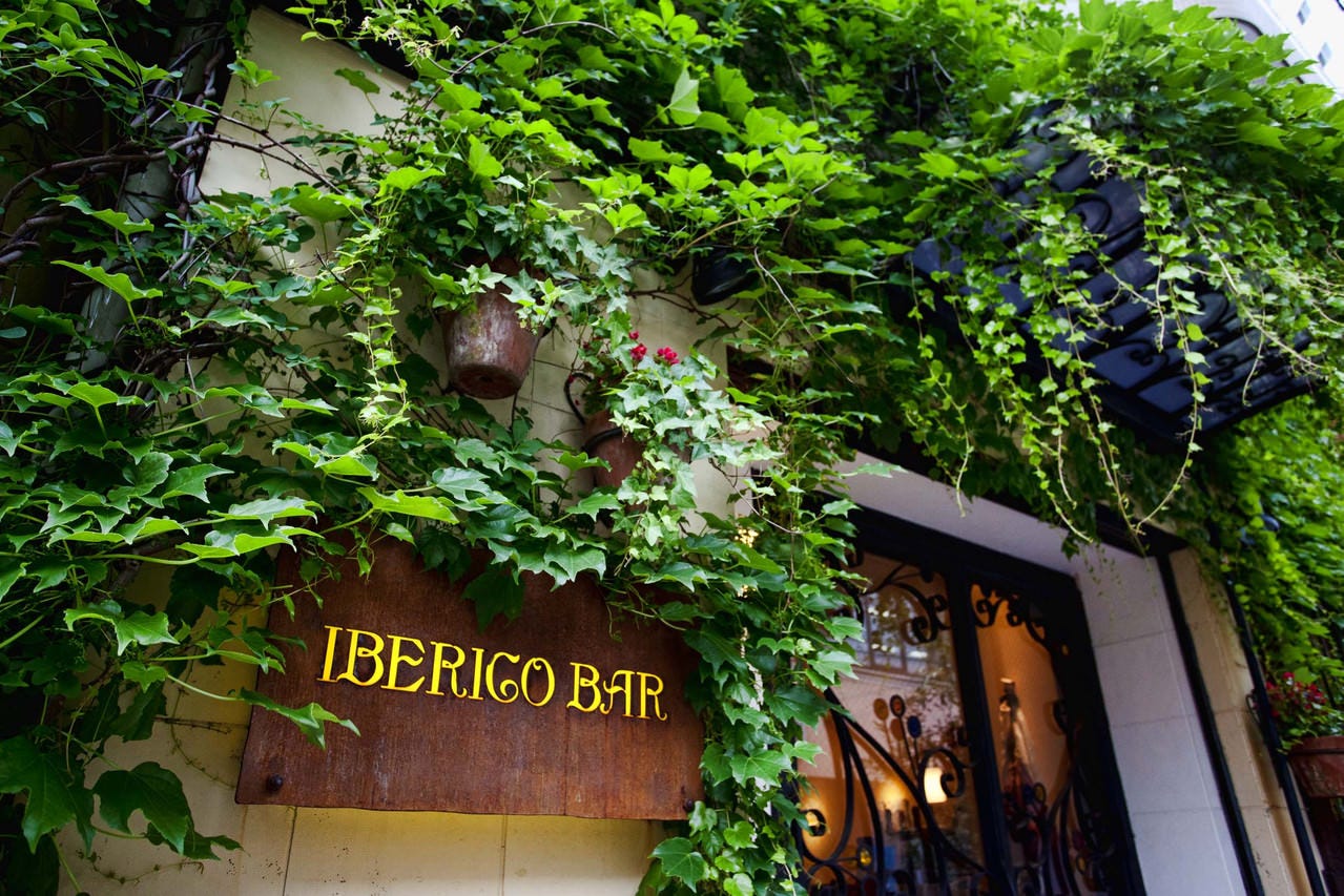 緑の蔦に覆われ、木の看板がおしゃれな雰囲気を演出する外観