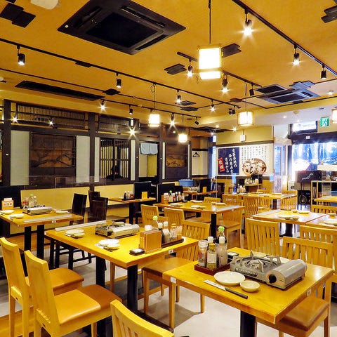 イエローを基調としたテーブルとイスが並ぶさかな酒場 魚星 中野駅北口店店内