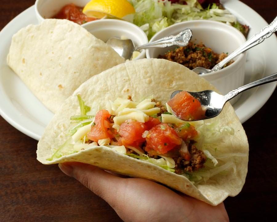 カフェ アンド ダイナー ケーエイチビーのタコスにトッピングをしている様子