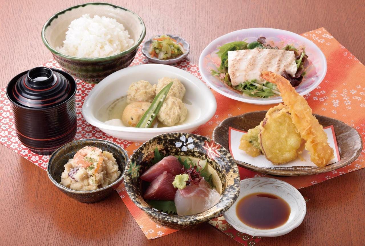 テーブルにのった家製豆腐のサラダ・小鉢・自慢のお刺身・温物・天ぷら盛・ごはん・味噌汁・香物