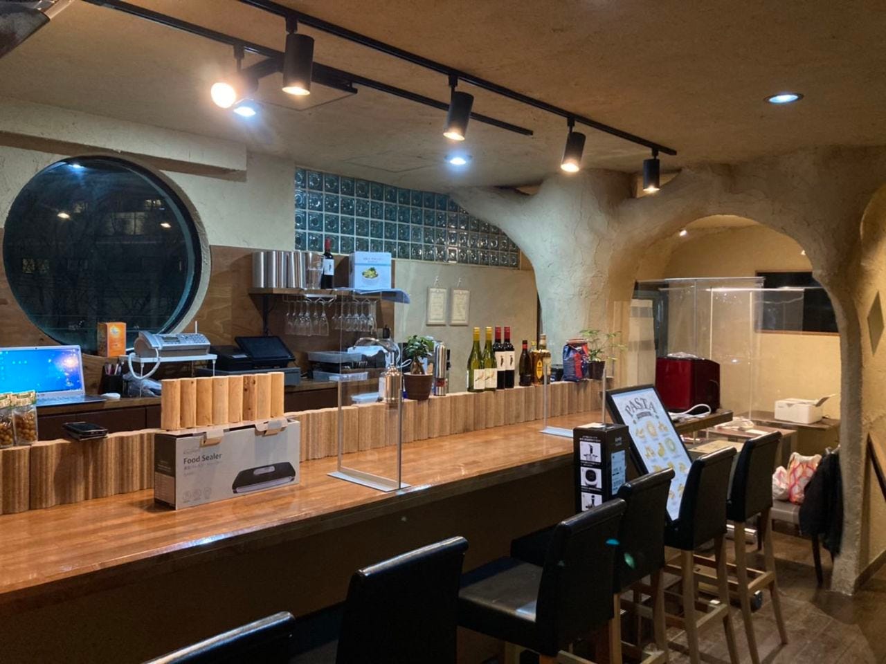 スポットライトに照らされた木のカウンター席のあるブラッスリー アシヤ ベッチー37の店内