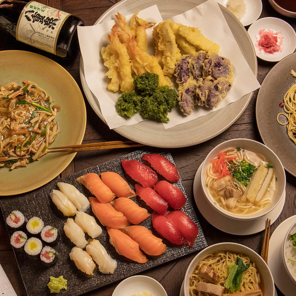 テーブルの上に寿司や天ぷら、沖縄そばなどが置かれている