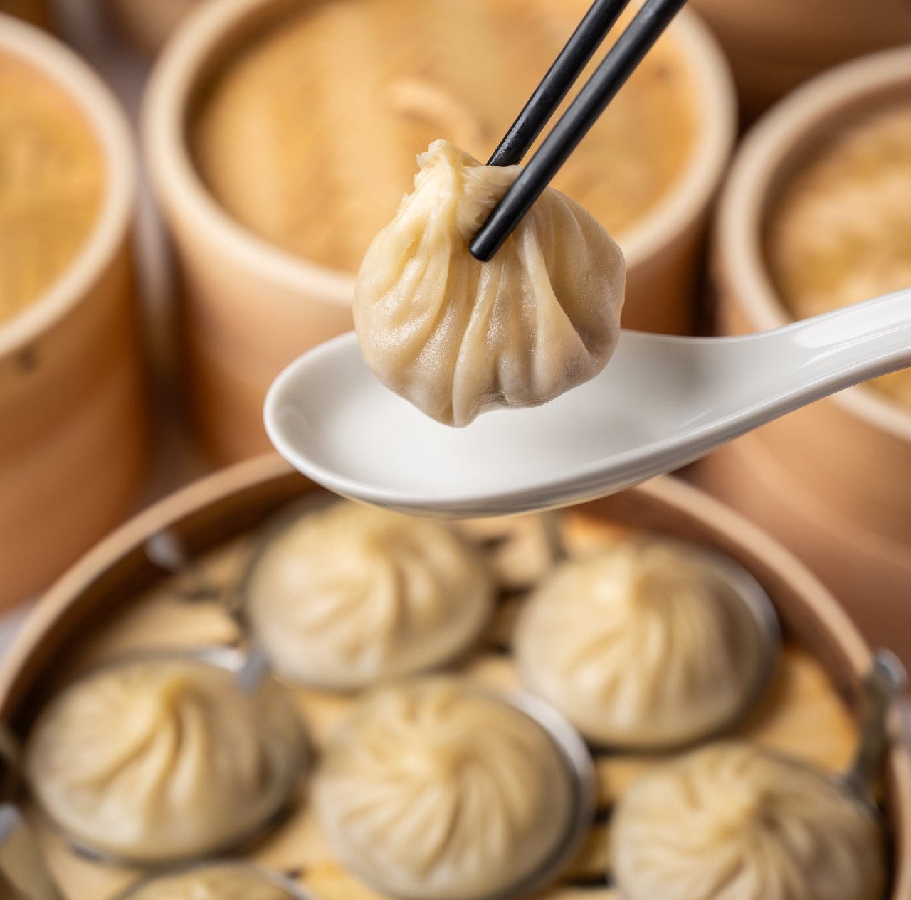 せいろに並んだ小籠包と箸で持ち上げられた小籠包