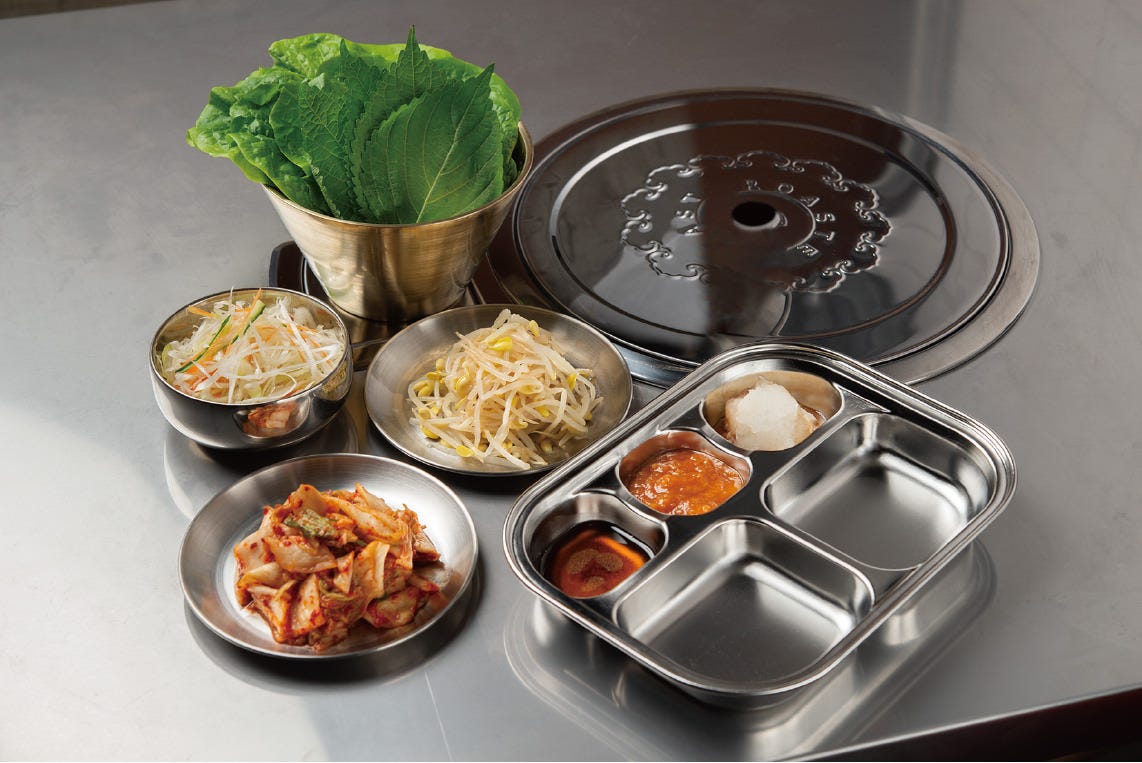 銀の皿に野菜と韓国料理が盛られた包み野菜食べ放題