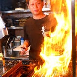 豪快な火柱を上げて焼き上げる「さつま知覧鶏の炙り焼き」