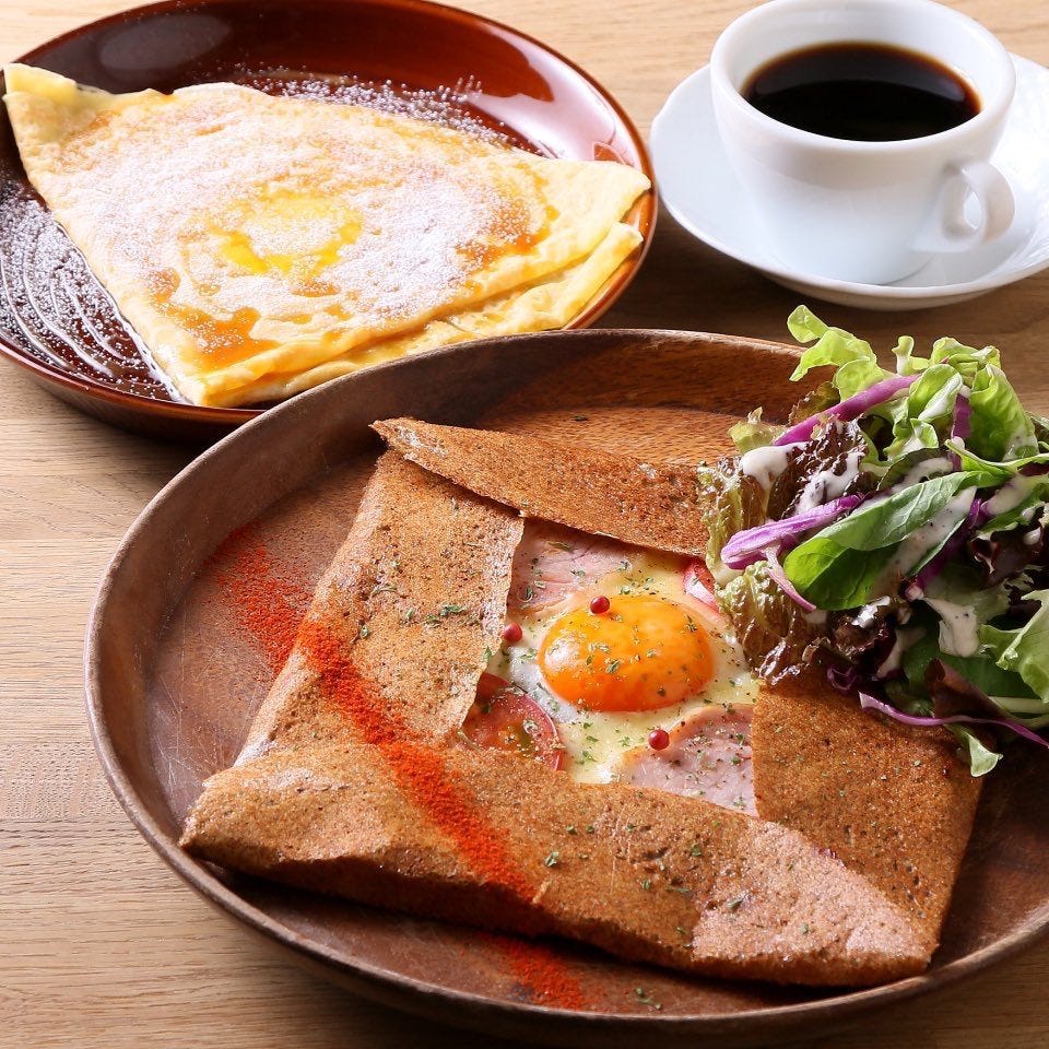 テーブルに並んだ卵とハムのガレットとクレープとコーヒー