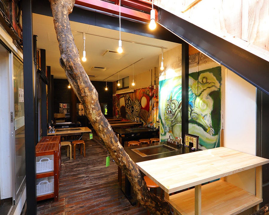 大きな木や壁一面のアートが印象的な原宿さくら亭内観
