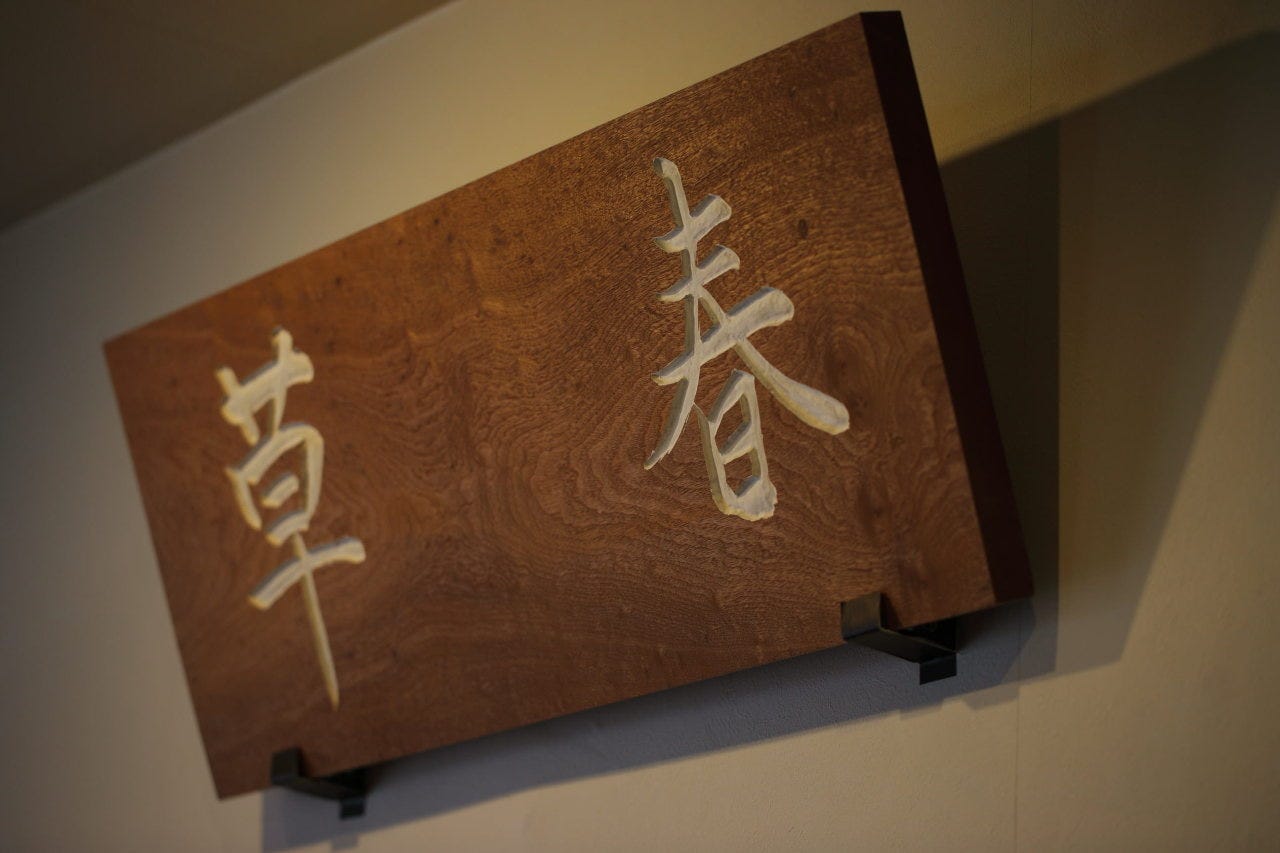 店内の壁に掲げられた扁額。店名は禅語の「春来草自生」に由来。