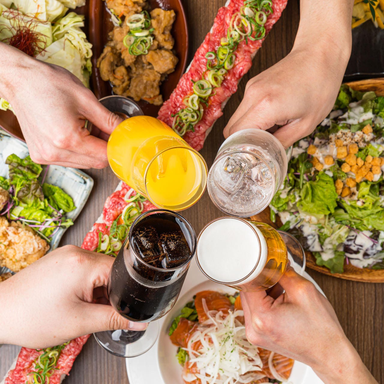 まんぷく屋 難波千日前店の料理とドリンクで乾杯する様子