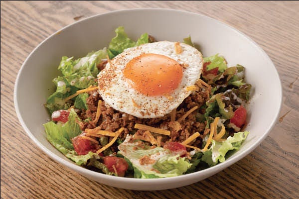 白い皿にはいった目玉焼きがのったタコライス