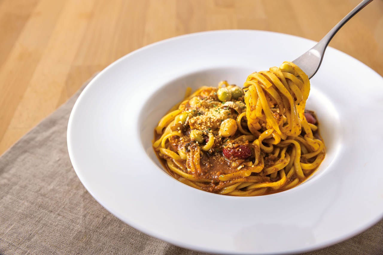 白い皿にもられたパスタをフォークですくっている