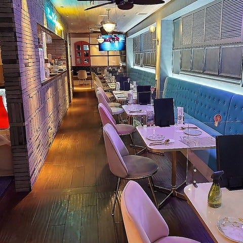 暗い照明で韓国のお店らしさのある店内に並ぶ白いテーブルと椅子