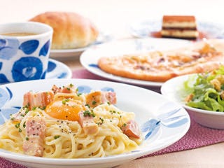 テーブルの上にカルボナーラやパンが乗っている