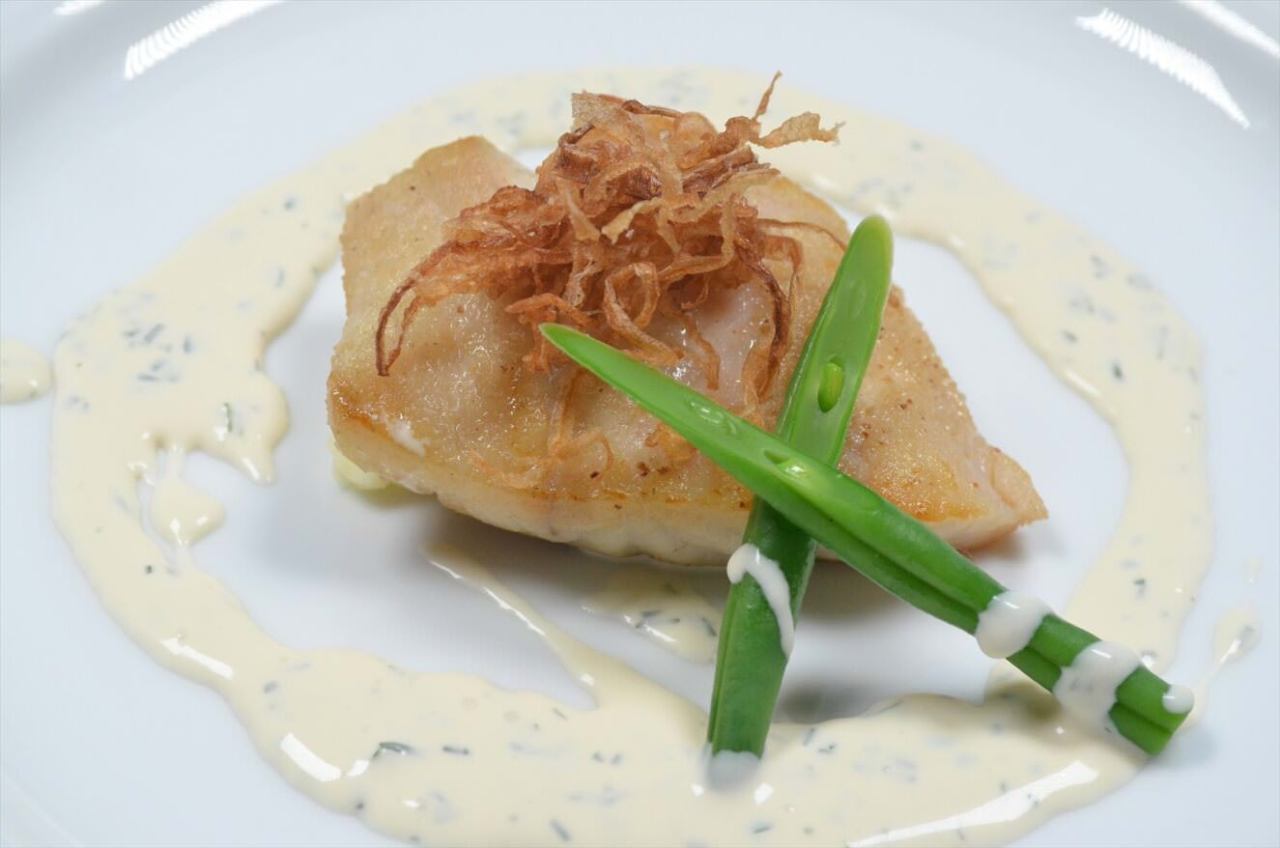 白いお皿に盛り付けられたスズキのポワレ 白ワインと香草のクリームソース