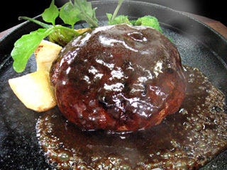 デミグラスソースがかかっている鉄板の上にのった黒毛和牛とイベリコ豚のハンバーグステーキ