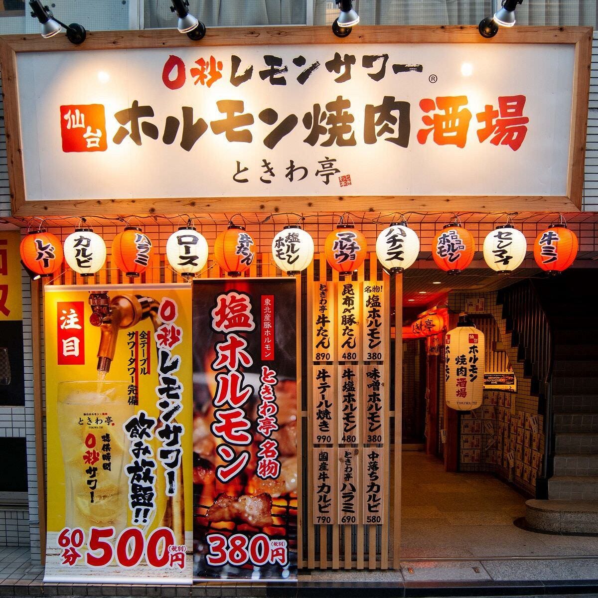 ホルモン焼肉酒場ときわ亭の店頭。提灯と、名物の塩ホルモンとレモンサワー飲み放題の看板が掲げられている。
