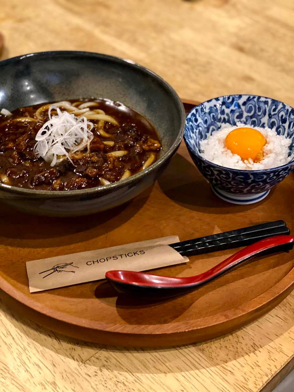 おぼんにキーマカレーうどんとたまごごはんが乗っている様子