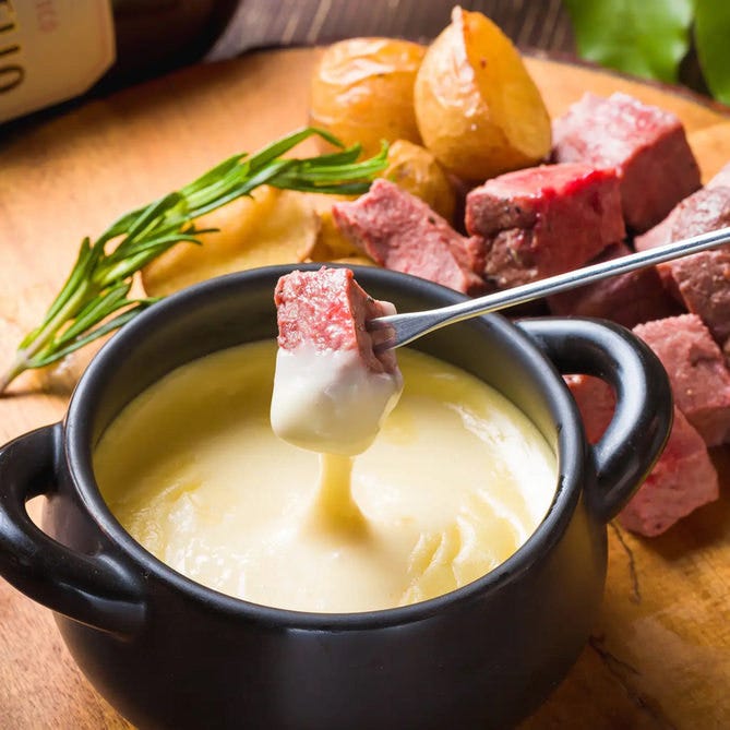 チーズフォンデュにサイコロステーキをつけている様子