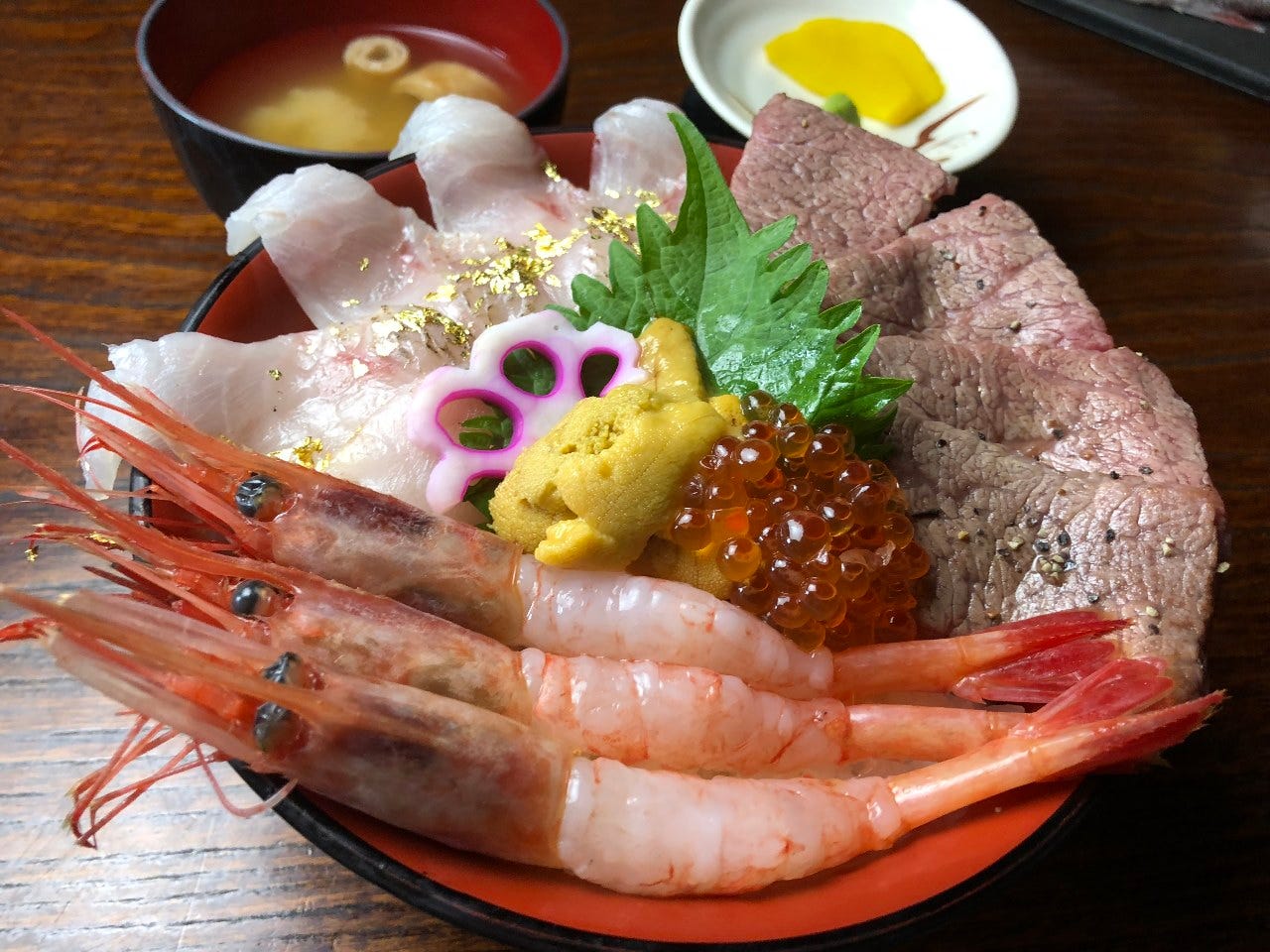 テーブルの上に丼に盛られた刺身屋の「海鮮牛丼」とみそ汁、たくあんが置かれている
