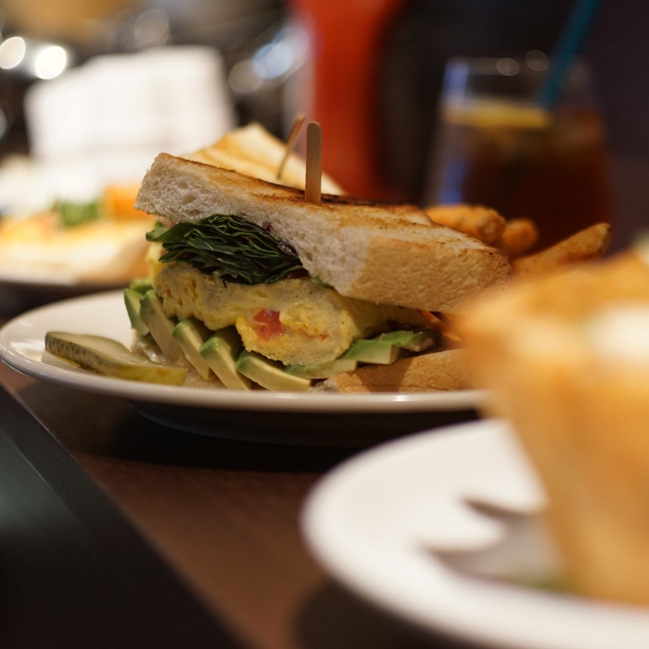 茶色のテーブルに置かれたアボカドエッグサンドウィッチ