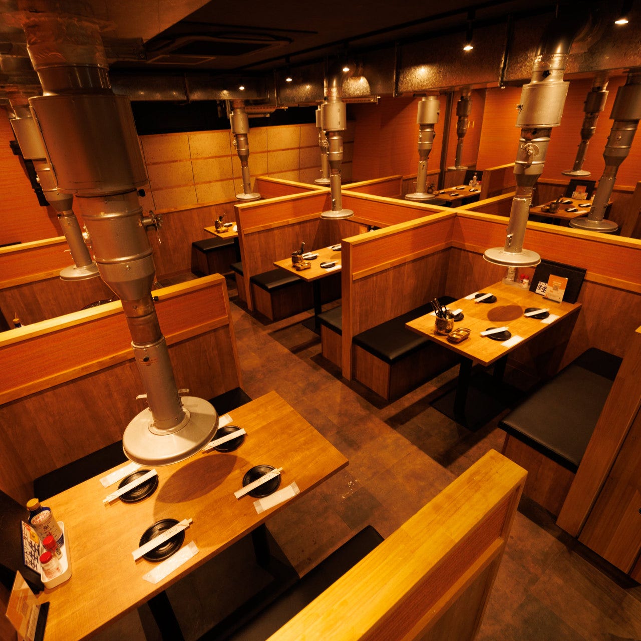 木目調のテーブルと椅子が複数並んだ牛若丸 池袋本店の店内