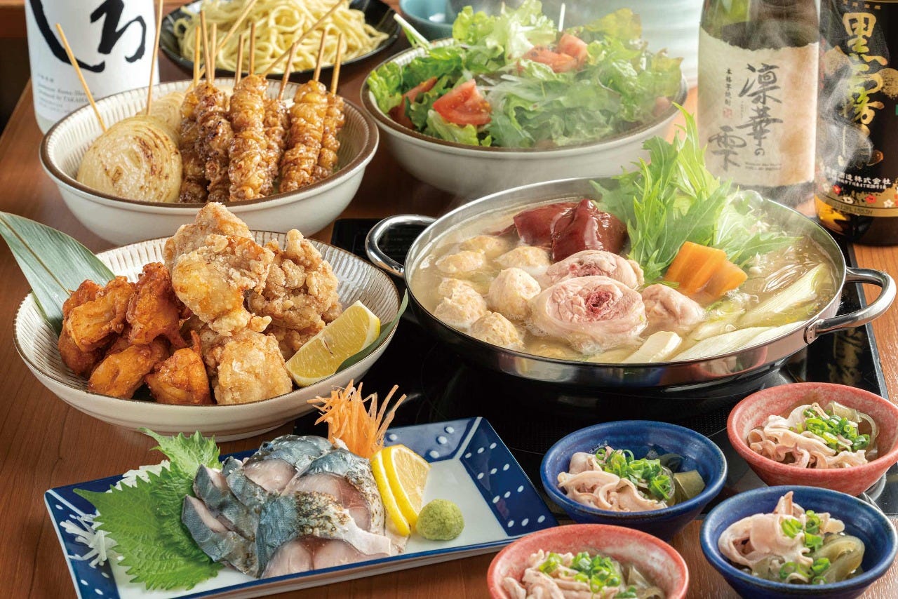 焼き鳥や水炊き、刺身や唐揚げなどのメニューが並ぶテーブル