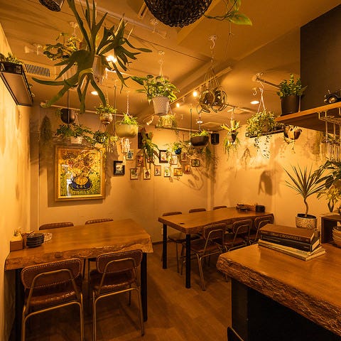 ウッド調のテーブル・椅子と天井から吊るされたたくさんの観葉植物